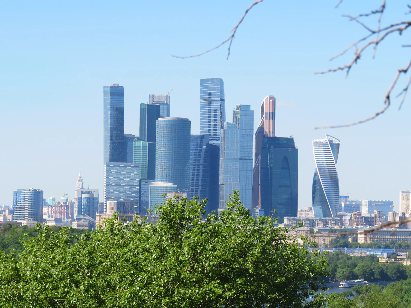 Башни Москва-Сити за зелёными деревьями
